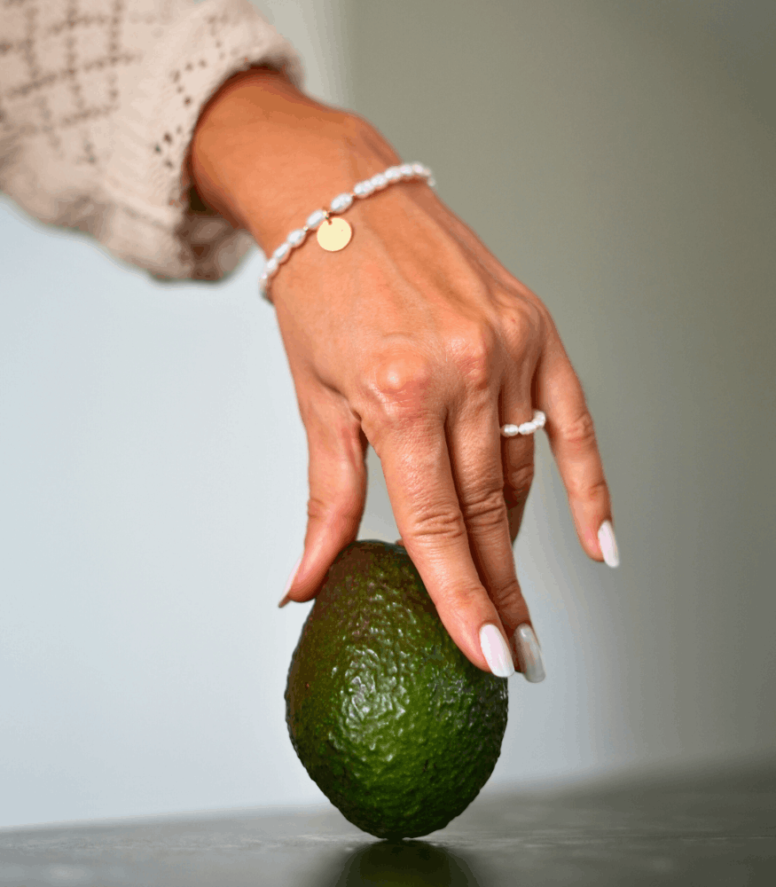 Produktfotografie Perlenarmband und Perlenring an einer Hand mit Avocado